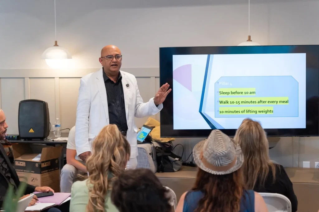Dr. Sal explaining a slide on sleep and meal timing at a live workshop